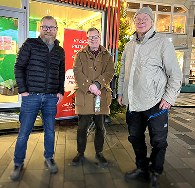 Ambassadörerna Cleas, Micke och Curt i vinterkläder utanför skyltfönster.