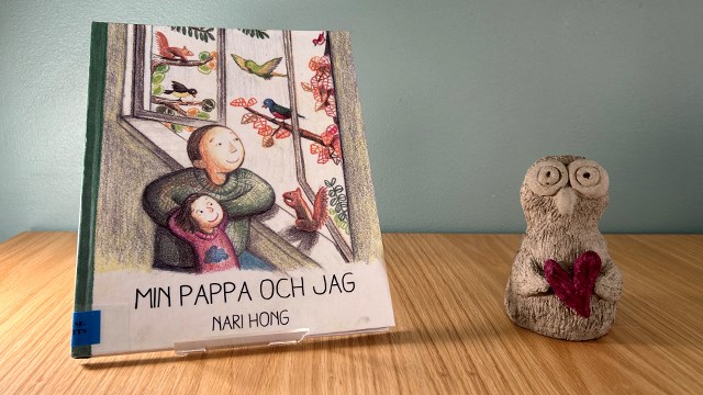 Bokomslag: Min pappa och jag. Illustration där vuxen och barn tittar ut genom öppet fönster. Utanför syns träd och fåglar.