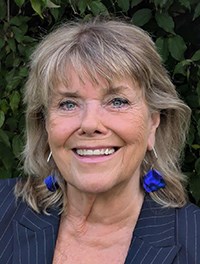 Portr&auml;ttbild Maud framf&ouml;r ett gr&ouml;nt l&ouml;vverk.