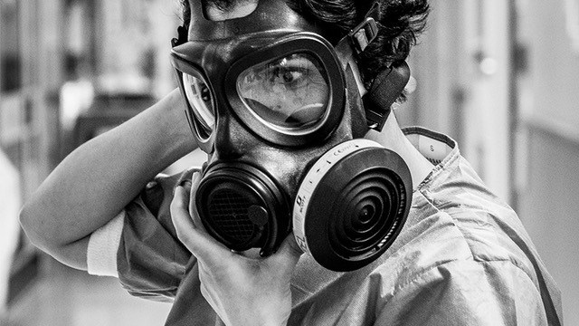 Svartvid bild på vårdpersonal med gasmask