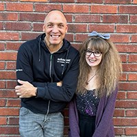 Rebecca Albrektsson och Niklas Rossi vid en tegelv&auml;gg tittar mot kameran.