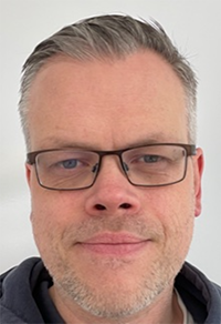 Porträttbild Thomas Westin med kort melerat hår och glasögon.