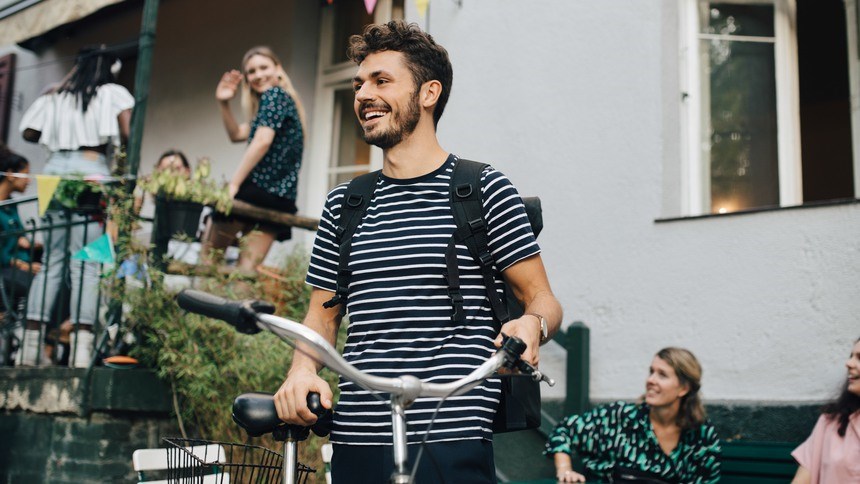 Ung man bredvid cykel omgiven av människor