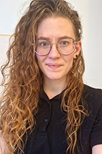 Karin med långt lockigt brunt hår som faller ner på ena sidan av huvudet.