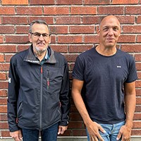 Anders Johansson och Niklas Rossi vid en tegelv&auml;gg tittar mot kameran.