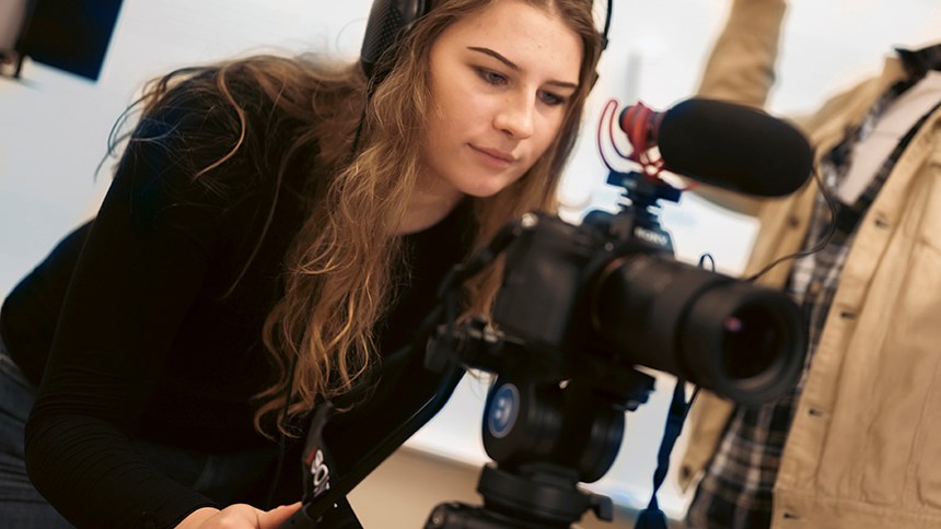 Ung kvinna filmar med filmkamera 