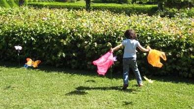 Foto på barn som springer med tyger i händerna i grönt gräs