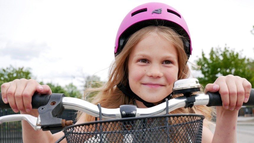 Ung flicka på cykel i rosa cykelhjälm