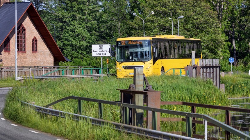Buss åker på landsväg över en å