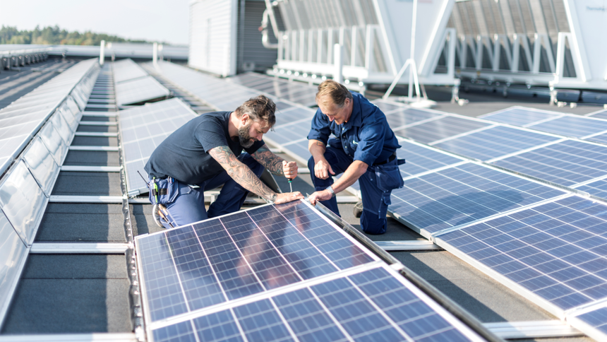 Två personer arbetar med solceller på tak