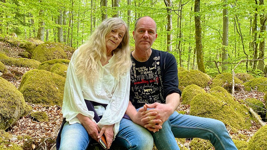 Man och kvinna i vardagskläder sitter på en sten ute i skogen
