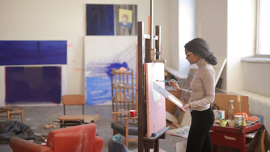 Kvinna står vid ett staffli och målar