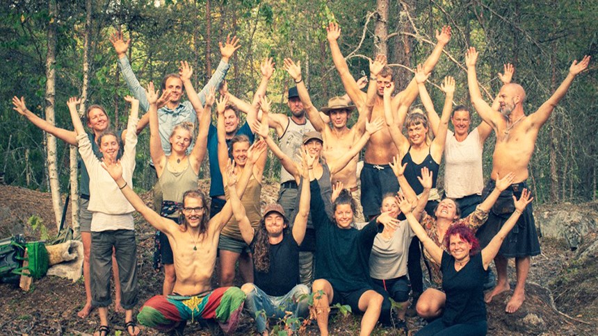Gruppfoto i skogen på personer med armarna i luften 